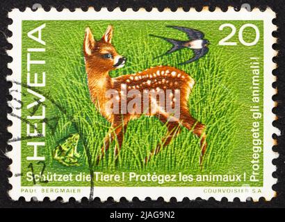 SCHWEIZ - UM 1976: Eine in der Schweiz gedruckte Marke zeigt Fawn, Frosch und Schwalbe, Wildlife Protection, um 1976 Stockfoto