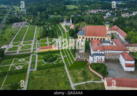 30. Mai 2022, Brandenburg, Neuzelle: Der Klostergarten des Klosters Neuzelle (Luftaufnahme mit Drohne). Im Klostergarten Neuzelle im oder-Spree-Kreis laufen seit rund zwei Jahren die Arbeiten an der dritten und letzten Bauphase zur Sanierung des Barockgeländes. Die Eröffnung ist für 10.06.2022 geplant. Hier entstanden eine Baumschule mit Gewächshaus, Küchengarten und Kräutergarten sowie symmetrisch angelegte Blumenbeete, die mit Hecken und Obstbäumen gesäumt sind. Seit 1998 wird an dem fast 5 Hektar großen Gartenkomplex gearbeitet, der sich als Konsid gilt Stockfoto