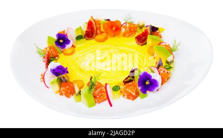 Leckere Lachstartare mit Ring aus frischem Gemüse und Blumen auf dem Teller Stockfoto