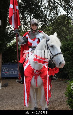 Ritter in glänzender Rüstung auf weißem Pferd zurück in Warwick Castle, Warwickshire, England, Großbritannien, 2022 Stockfoto