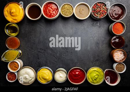 Set aus verschiedenen Schüsseln mit verschiedenen Dip-Saucen, auf dunklem Hintergrund, Draufsicht Stockfoto