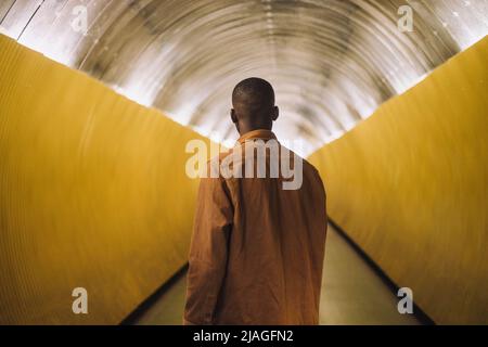 Rückansicht eines jungen Mannes, der im U-Bahn-Tunnel stand Stockfoto