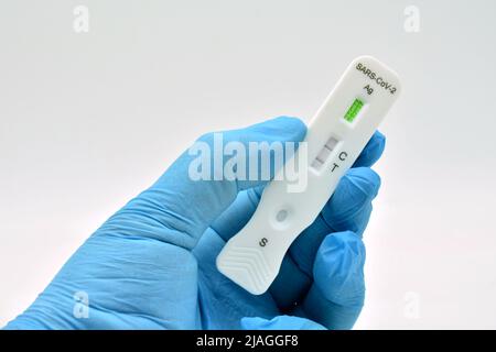 Mano con guante sujetando un Test de antígenos, que ha dado positive en covid 19 Stockfoto