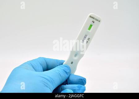 Mano con guante sujetando un Test de antígenos, que ha dado positive en covid 19 Stockfoto