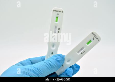 Mano con guante sujetando un Test de antígenos, que ha dado positive en covid 19 Stockfoto