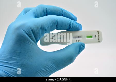 Mano con guante sujetando un Test de antígenos, que ha dado positive en covid 19 Stockfoto