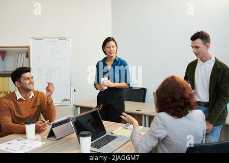 Gruppe von Geschäftsleuten, die sich bei einem Treffen im Büro unterhalten, Ideen austauschen und Nachrichten diskutieren Stockfoto