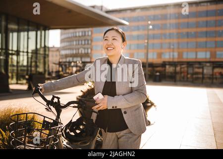 Glückliche weibliche Profi-Wheeling Fahrrad auf dem Fußweg während sonnigen Tag Stockfoto