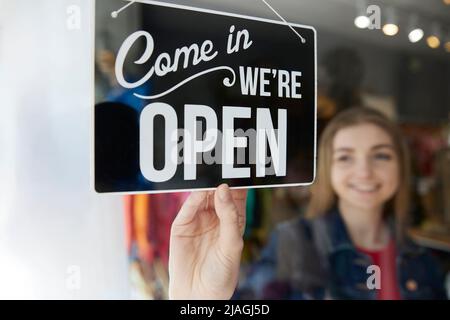 Lächelnde Inhaberin Eines Kleinbetriebes, Die Das Schild Im Schaufenster Öffnet Stockfoto