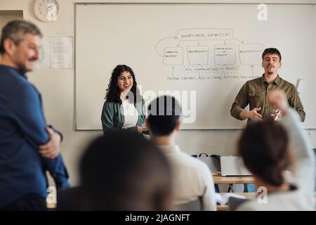 Männliche und weibliche Schüler, die während der Q- und Einer Unterrichtsstunde mit Freunden interagieren Stockfoto