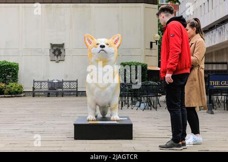 London, Großbritannien. 30.. Mai 2022. Die Menschen betrachten und fotografieren einen der riesigen Corgis, die vor der Royal Military Chapel in der Nähe der Wellington Barracks in Westminster installiert sind. Der Corgi Trail, auch bekannt als 'The Queen & her Corgis', ist ein Kunstprojekt, das aus 19 riesigen Corgi-Statuen besteht, die während des Jubiläums von zeitgenössischen Künstlern in öffentlichen Räumen platziert wurden. Kredit: Imageplotter/Alamy Live Nachrichten Stockfoto