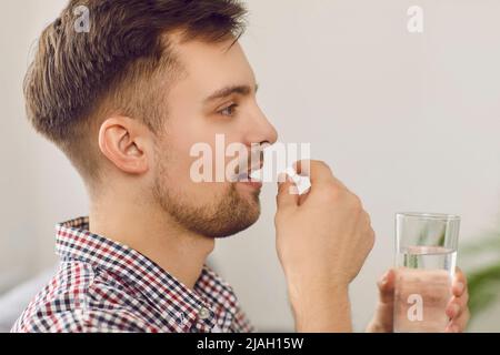 Nahaufnahme eines jungen Mannes, der verschriebene Medikamente eingenommen und ein Glas Wasser getrunken hat Stockfoto