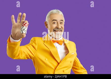 Lächelnder, gealterter Mann mit Casino-Chips in den Händen Stockfoto