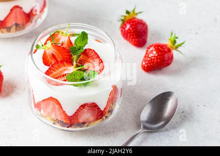 Erdbeerparfait mit Joghurt und Müsli in einem Glasgefäß. Gesundes Frühstücksrezept. Sommerliches Dessert-Konzept. Stockfoto