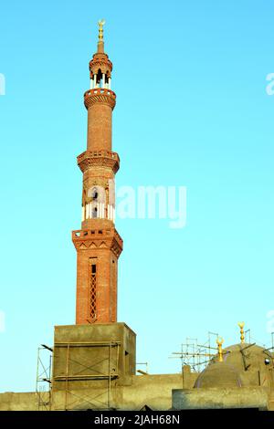 Ein hohes Minarett mit goldenem Ornament einer Moschee, die im Bau ist, Minarett oder Turm, der nach Himmel, islamischer Religion und Architektur strebt Stockfoto