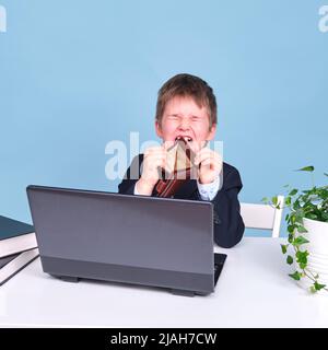 Ein Junge in einem Schulanzug mit einer leeren Brieftasche, kopieren Sie Platz auf einem blauen Studiohintergrund Stockfoto