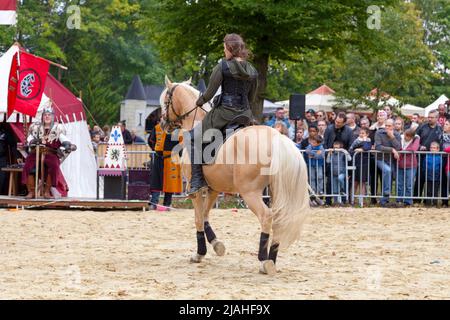 Luzarches, Frankreich - 12 2019. Oktober: Eine mittelalterliche Frau auf ihrem Pferd paradiert vor ihrem König während des jährlichen Médiévales-Festivals. Stockfoto