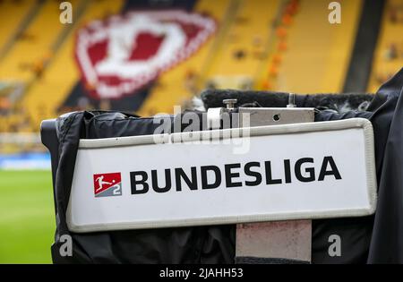 24. Mai 2022, Sachsen, Dresden: Fußball: 2. Bundesliga - Abstieg, SG Dynamo Dresden - 1. FC Kaiserslautern, zweite Etappe im Rudolf-Harbig-Stadion. An einer Fernsehkamera im Stadion hängt ein Bundesliga-Schild. Nach der Niederlage gegen Kaiserslautern wird die SGD in die Dritte Liga abgesetzt. Foto: Jan Woitas/dpa - WICHTIGER HINWEIS: Gemäß den Anforderungen der DFL Deutsche Fußball Liga und des DFB Deutscher Fußball-Bund ist es untersagt, im Stadion und/oder des Spiels aufgenommene Fotos in Form von Sequenzbildern und/oder videoähnlichen Fotoserien zu verwenden oder zu verwenden. Stockfoto