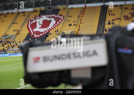 24. Mai 2022, Sachsen, Dresden: Fußball: 2. Bundesliga - Abstieg, SG Dynamo Dresden - 1. FC Kaiserslautern, zweite Etappe im Rudolf-Harbig-Stadion. An einer Fernsehkamera im Stadion hängt ein Bundesliga-Schild. Nach der Niederlage gegen Kaiserslautern wird die SGD in die Dritte Liga abgesetzt. Foto: Jan Woitas/dpa - WICHTIGER HINWEIS: Gemäß den Anforderungen der DFL Deutsche Fußball Liga und des DFB Deutscher Fußball-Bund ist es untersagt, im Stadion und/oder des Spiels aufgenommene Fotos in Form von Sequenzbildern und/oder videoähnlichen Fotoserien zu verwenden oder zu verwenden. Stockfoto