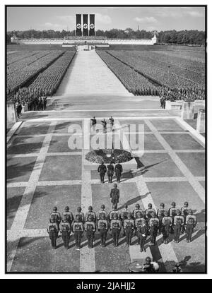 NÜRNBERGER KUNDGEBUNG 1930s 1934 Adolf Hitler, Heinrich Himmler und Viktor Lutze auf dem Gelände der NSDAP während der Nürnberger Kundgebung 1934, dem NSDAP-Kongress 6., der vom 5. Bis 10. September in Nürnberg stattfand und an dem rund 700.000 Anhänger der NSDAP teilnahmen. Auch Mitglieder der paramilitärischen Parteizweige Sturmabteilung (SA) und Schutzstaffel (SS), sowie der Blutfahne (Blutflagge, zeremonielle Hakenkreuzflagge) und wahrscheinlich deren Träger SS-Sturmbannführer Jakob Grimminger. : Die große Anziehungskraft der S.A. und S.S. vor dem Führer in der Luitpold Arena in Nürnberg. Nazi-Deutschland Stockfoto