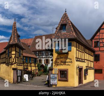 Eguisheim, Frankreich - 29. Mai 2022: Historische bunte Fachwerkhäuser und Weinkeller im Dorfzentrum von Eguisheim Stockfoto