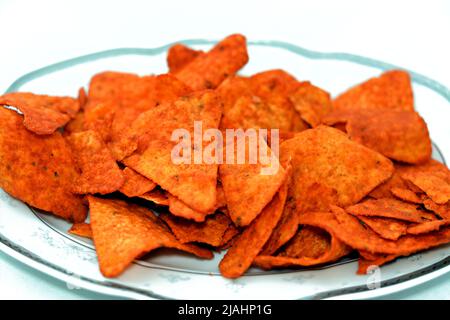 Ein Stapel aromatisierter Tortilla-Chips aus Mais-Tortillas, die in Dreiecke geschnitten und dann gebraten oder gebacken wurden, serviert in einer ovalen Servierplatte, die auf weißem Ba isoliert ist Stockfoto