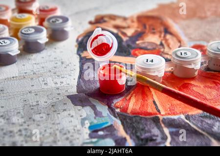 Halb gemalte Malerei nach Zahlen mit Acrylfarbe Gläser und ein Pinsel. Selektiver Fokus, Lichtunschärfe, Unschärfe. Stockfoto