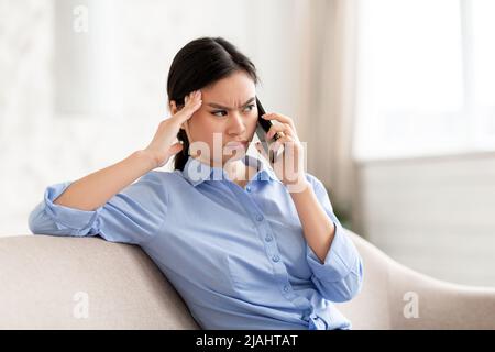 Verärgerte chinesische Dame, die ein Telefongespräch führt und den Platz der Kopie anschaut Stockfoto