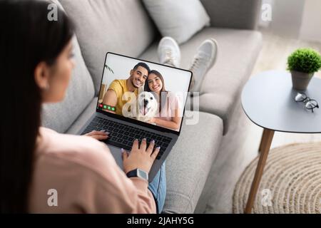 Junge Dame, die mit ihren Freunden eine Videokonferenz mit einem Laptop veranstaltet Stockfoto
