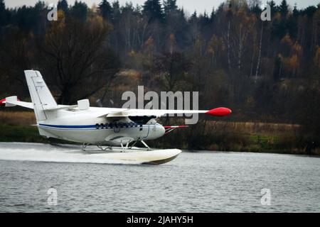 Das zweimotorige Wasserflugzeug ein Wasserflugzeug steigt aus dem Wasser, aus dem Waldsee, dem nördlichen Land auf. Wasserflugzeug Stockfoto