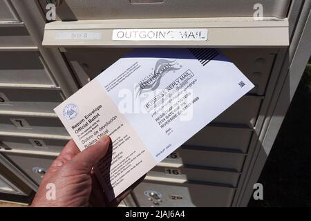 Lake Elsinore, CA, USA - 30. Mai 2022: Nahaufnahme eines Mannes, der Wahlurnen per Post in der Briefkastenbox platziert. Stockfoto