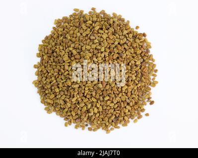 Stapel von Fenugreek-Samen auf weißem Hintergrund. Viele ganze Bockshornkleesamen aus der Nähe, kulinarische Zutat. Stockfoto