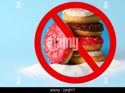 Süße Donuts und Verbotsschild auf hellblauem Hintergrund. Kein Zucker Stockfoto