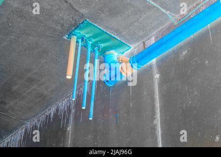 Installation von Wasser- und Abwasserleitungen in der technologischen Öffnung der Zwischenbodenüberlappung des Kellergeschosses, selektiver Fokus und negativ Stockfoto