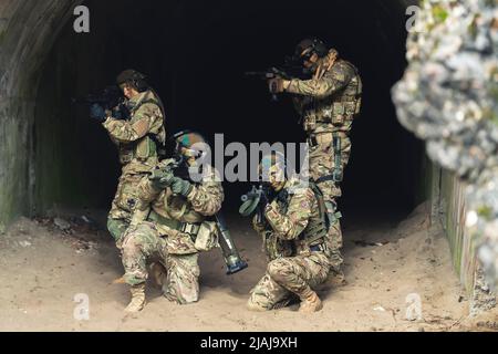 Teamwork-Konzept. Eine Gruppe von Soldaten, die in Tarnung gekleidet waren, schaute sich mit ihrer Schusswaffe um. Außenaufnahme. Hochwertige Fotos Stockfoto