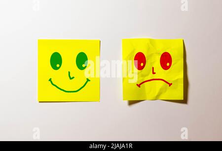 Glückliches und trauriges Gesicht, Emoticons auf dem grünen Hintergrund. Stockfoto