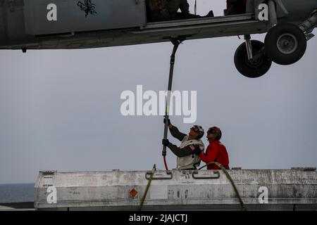 PHILIPPINISCHES MEER (20. Mai 2022) ADM hinten. JT Anderson, links, Commander, Carrier Strike Group (CSG) 3, legt einem Hubschrauber der MH-60s Sea Hawk, der den „Chargers“ von Helicopter Sea Combat Squadron (HSC) 14 zugewiesen wurde, während eines Munitionsübergangs mit dem Flugzeugträger USS Ronald Reagan der Nimitz-Klasse (CVN 76) Vom Deck des Flugzeugträgers USS Abraham Lincoln (CVN 72) der Nimitz-Klasse. Die Abraham Lincoln Strike Group befindet sich im geplanten Einsatzbereich der US-Flotte für 7., um die Interoperabilität durch Allianzen und Partnerschaften zu verbessern und gleichzeitig als Ready-RE zu dienen Stockfoto