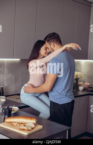 Porträt eines verliebten Paares umarmt sich zu Hause im Inneren. Mann und Frau umarmen in der Küche. Stockfoto