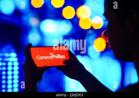 Brasilien. 30.. Mai 2022. In dieser Abbildung hält eine Frau mit Silhouetten ein Smartphone mit dem ConocoPhilips Logo auf dem Bildschirm. (Foto von Rafael Henrique/SOPA Images/Sipa USA) Quelle: SIPA USA/Alamy Live News Stockfoto