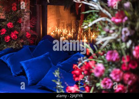 Bett mit Kamin mit Blumen und Kerzen dekoriert. Stockfoto