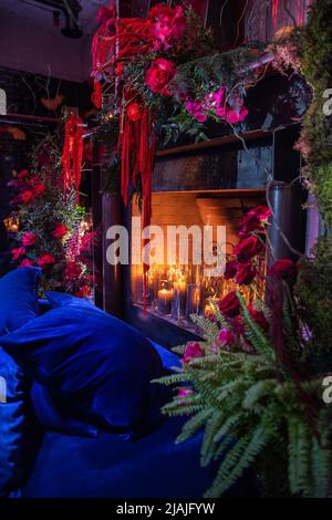 Helle Blumen in der Nähe des Kamins mit Kerzen. Stockfoto