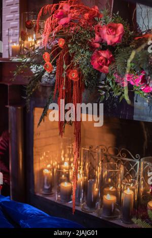 Helle Blumen in der Nähe des Kamins mit Kerzen. Stockfoto