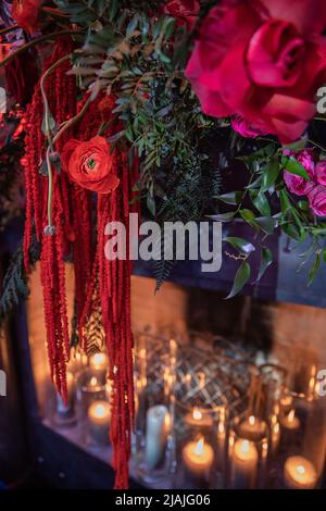 Helle Blumen in der Nähe des Kamins mit Kerzen. Stockfoto