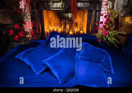 Bett mit Kamin mit Blumen und Kerzen dekoriert. Stockfoto