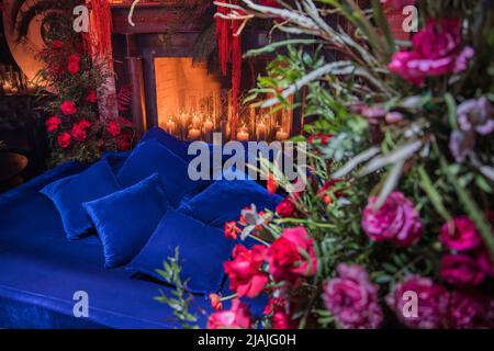 Bett mit Kamin mit Blumen und Kerzen dekoriert. Stockfoto