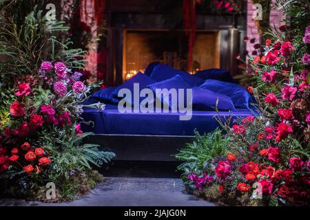 Bett mit Kamin mit Blumen und Kerzen dekoriert. Stockfoto