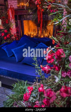 Bett mit Kamin mit Blumen und Kerzen dekoriert. Stockfoto
