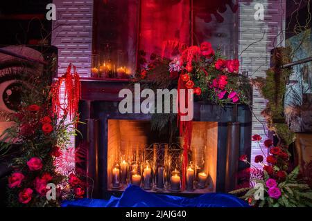 Helle Blumen in der Nähe des Kamins mit Kerzen. Stockfoto