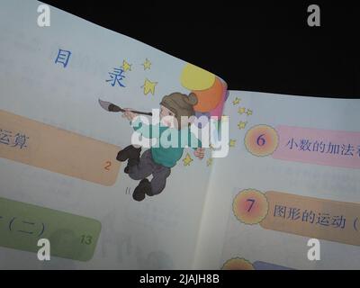YICHANG, CHINA - 31. MAI 2022 - Ein Bürger zeigt die Illustrationen des zweiten Bandes des veröffentlichten Mathe-Lehrbuchs der vierten Klasse für Grundschulen Stockfoto