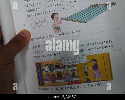 YICHANG, CHINA - 31. MAI 2022 - Ein Bürger zeigt die Illustrationen des zweiten Bandes des veröffentlichten Mathe-Lehrbuchs der vierten Klasse für Grundschulen Stockfoto